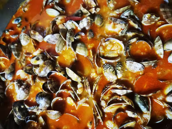 Almejas abriéndose en la salsa marinera